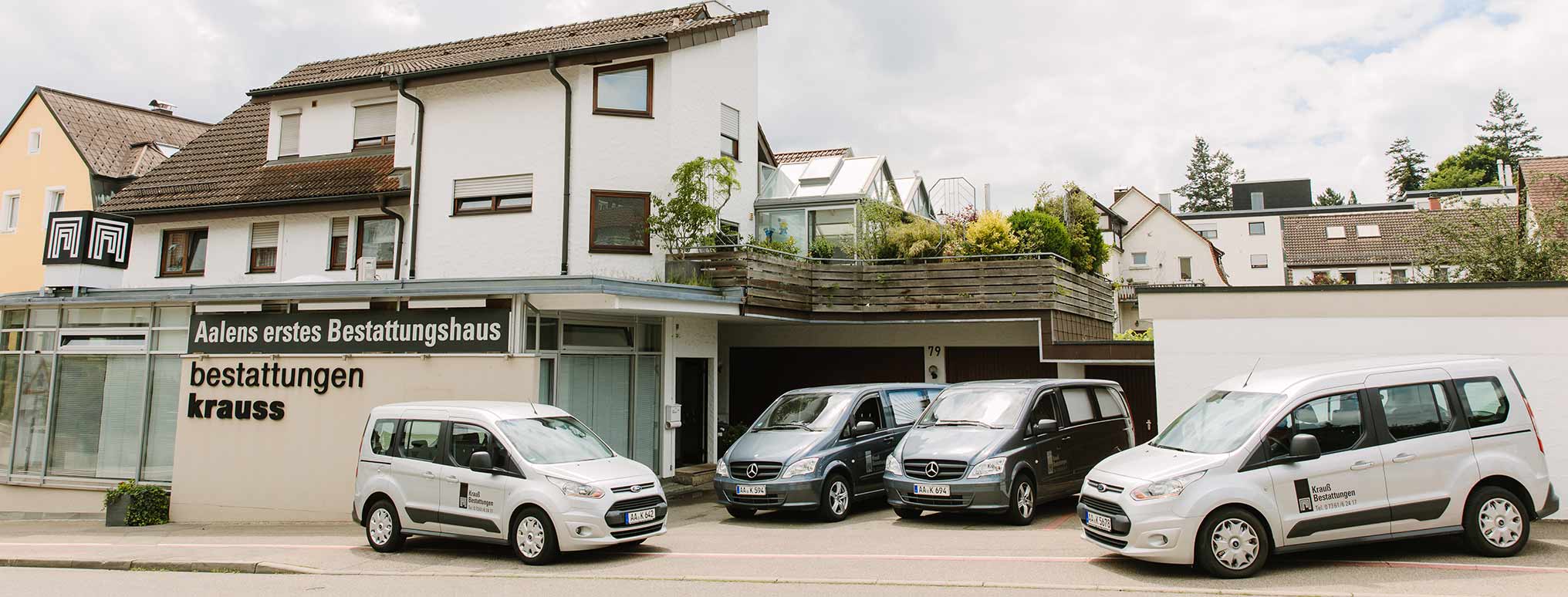 Außenansicht von Krauß Bestattungen in Aalen, mit mehreren Bestattungsfahrzeugen vor dem Gebäude.